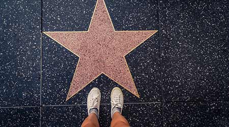Tourist photographing her with an empty star on the Walk of Fame in Hollywood. Hollywood Walk of Fame features more than 2,500 stars with inscribed celebrity names  O
