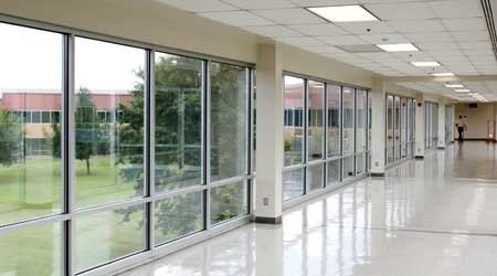 shine on finished floor in long hallway of facility with windows