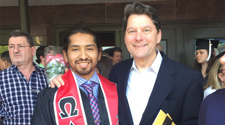 Middle-aged man takes picture with young man during a graduation ceremony