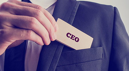 Retro style image of a businessman showing a wooden card reading - CEO - as he withdraws it from the pocket of his suit jacket