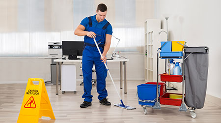 Full length of male janitor mopping floor in office