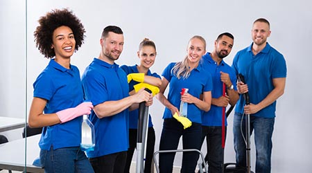 Happy Male And Female Janitors With Cleaning Equipment