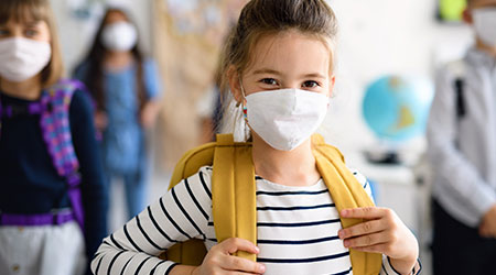 Child with face mask going back to school after covid-19 quarantine and lockdown.