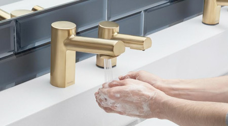 Gold-colored touchless restroom sink fixture