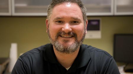 bearded man in casual shirt smiles