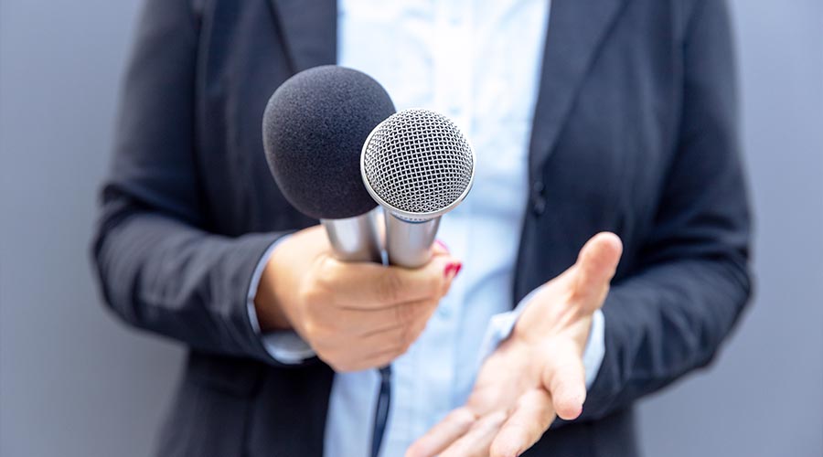 Journalist or TV reporter holding microphone and making media interview. Broadcast journalism concept.