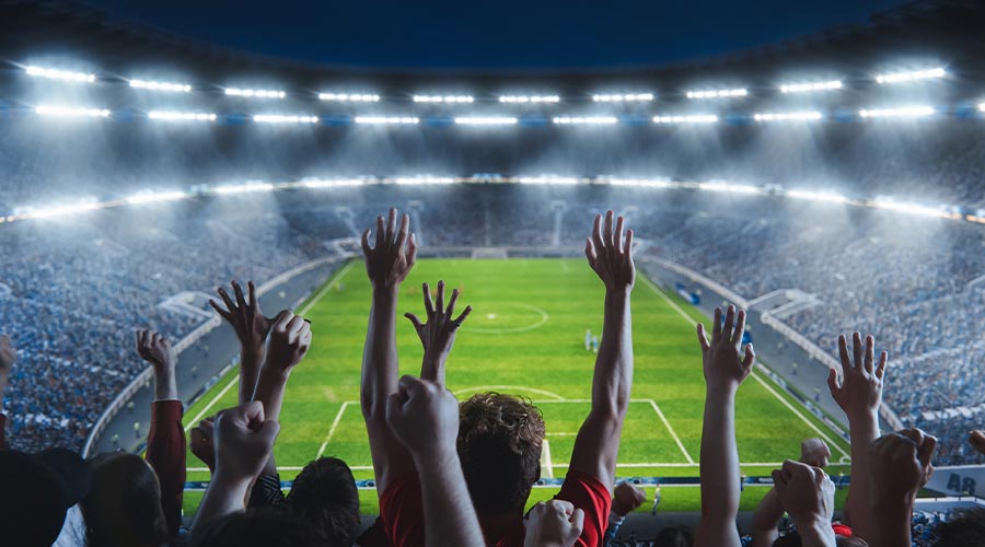 Silhouette of a fan in a crowded soccer stadium at night.